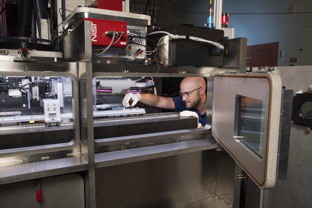 An expert with lab gloves reaches into a 3D printer to adjust the printing base
