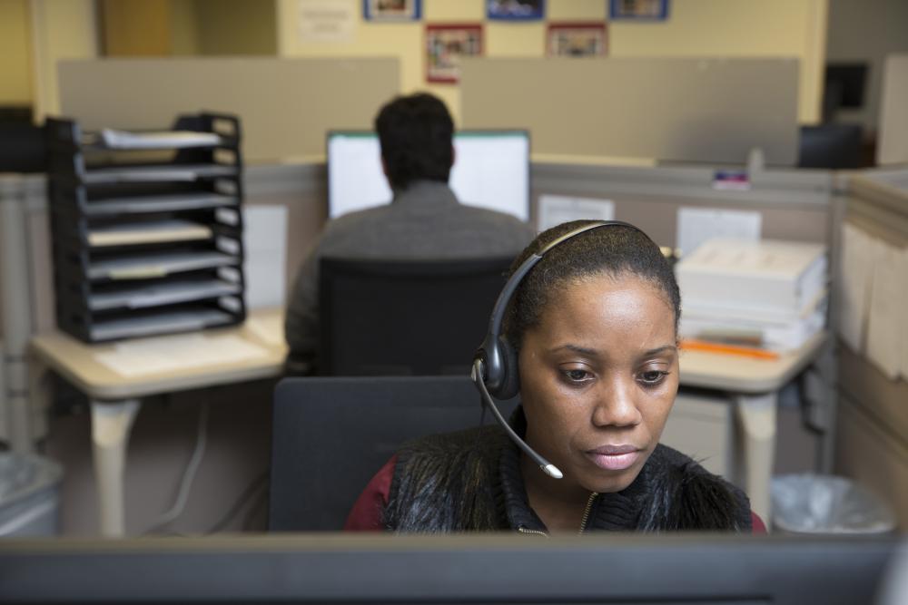 A Census call center employee wearing a headset looks at her computer screen.