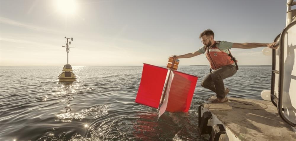 NOAA Research scientist Eric Anderson - 2019 PECASE Winner - deploys a drifter buoy from back of a research vessel in the Straits of Mackinac - NOAA Research photo 