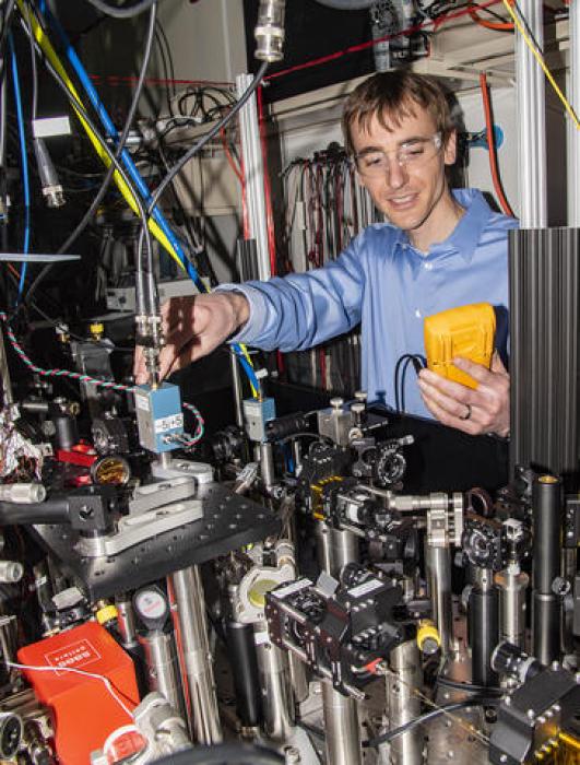 NIST physicist David Leibrandt adjusting one of the lasers used to operate the quantum logic clock, an experimental next-generation atomic clock based on the "ticking" of a single aluminum ion (electrically charged atom).  Credit: Burrus/NIST