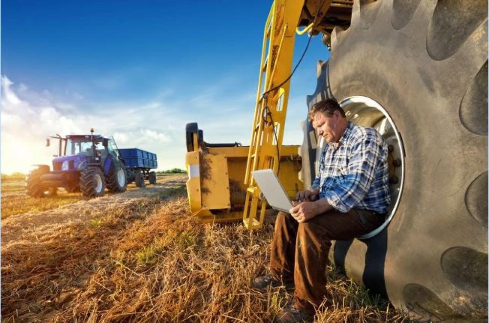 Photo of a farmer with laptop on rural land. 