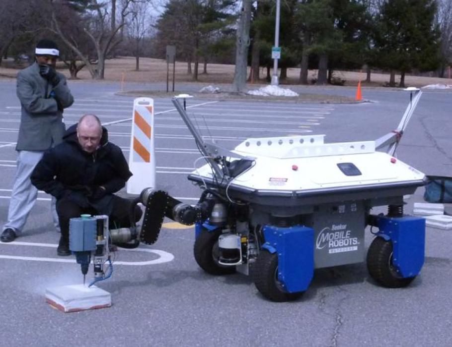 Visitors watch a Rutgers bridge repair robot go through its paces at a NIST meeting