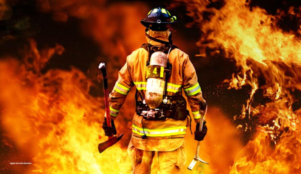Firefighter standing in front of flames