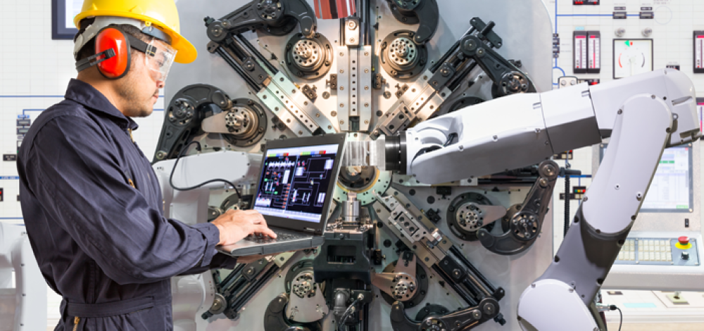 Photo of worker on laptop in manufacturing plant (Photo Credit: NIST). 