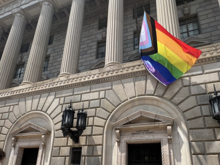 The Progress Pride flag flies in front of the U.S. Department of Commerce