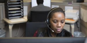 A Census call center employee wearing a headset looks at her computer screen.