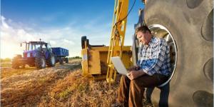 Photo of a farmer with laptop on rural land. 