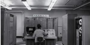 An African-American woman sits at the console of a FOSDIC (Film Optical Sensing Device for Input to Computers) device inputting data